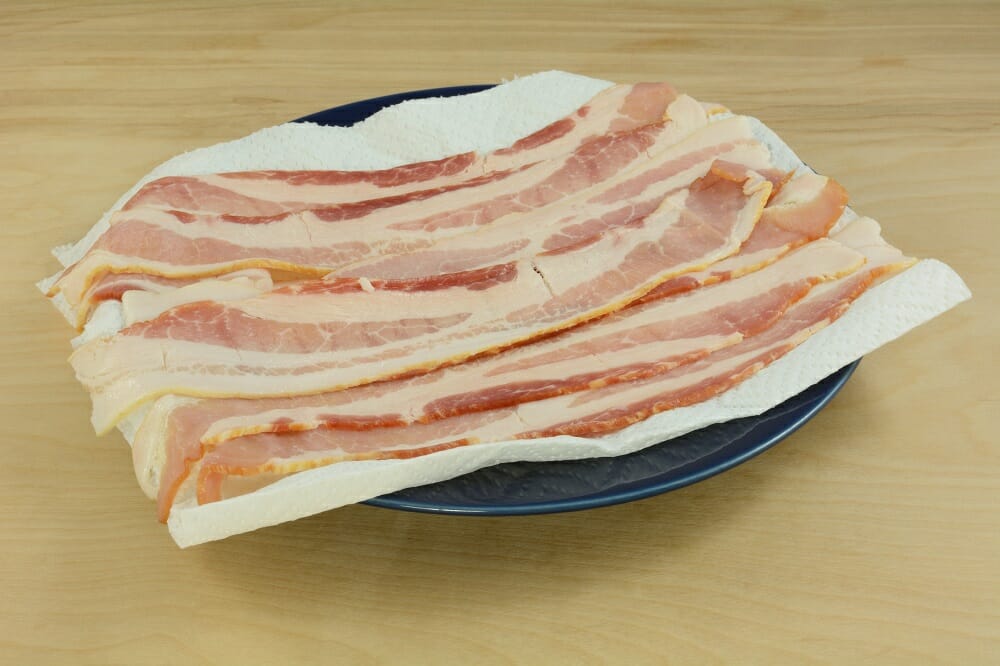 Raw,Bacon,Strips,On,Paper,Towel,On,Blue,Plate,In